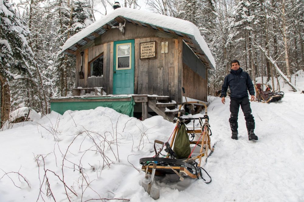 Voyageur et son traineau devant une cabane au Québec