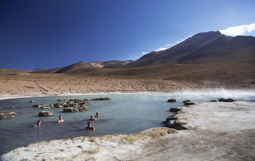 Randonneurs se délassant dans les sources d'eau chaude de Polloquere, reserve de Lauca, Chili