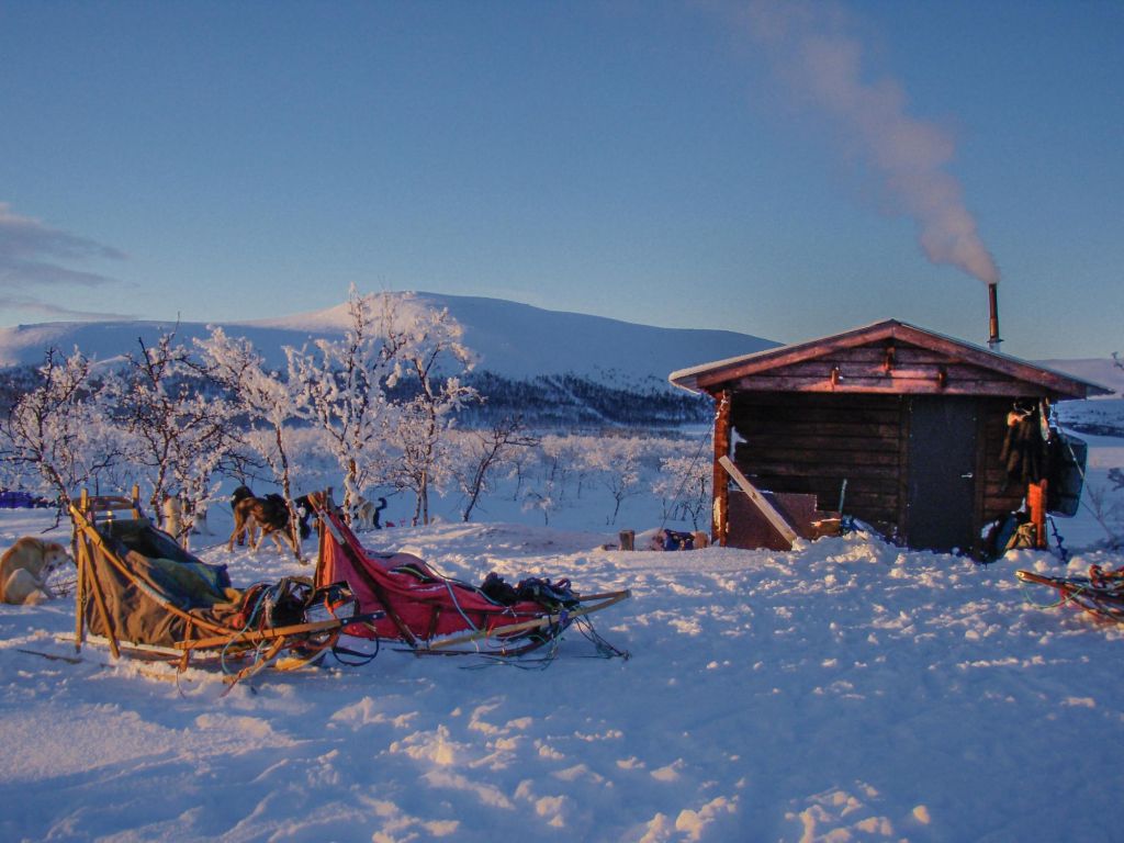 Cabane dans la neige avec traineaux devant